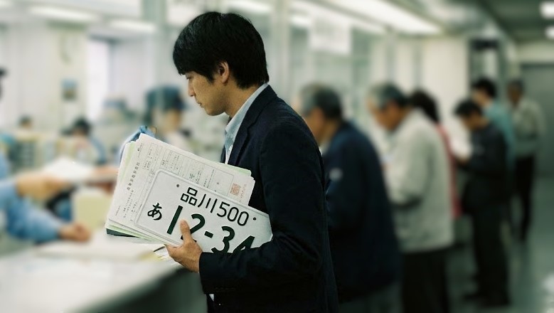 バイク廃車110番|ナンバープレートを持参して、原付バイクの廃車手続きを役所でする男性